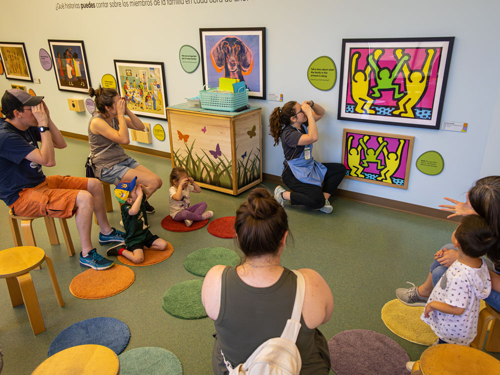 A group of people sitting on colorful rugs in Playscape art room.